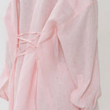 Blusa rosa estructurada con mangas largas y cintura atada.