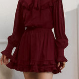 Elegante mini vestido de manga larga y encaje, adornado con lazo, corte trapecio.