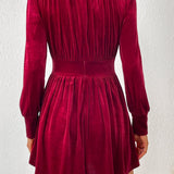 Vestido corto entallado de terciopelo con manga larga y escote en pico, abotonado.