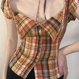 Blusa corta de cuadros, cintura ajustada, cuello con lazo y botones en la parte delantera.