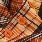 Blusa corta de cuadros, cintura ajustada, cuello con lazo y botones en la parte delantera.