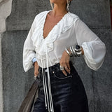 Blusa blanca con volantes, escote en pico y mangas farol.