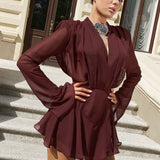 Vestido corto de gasa color burdeos con escote en pico y manga larga, talle alto.