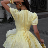Mini vestido de algodón amarillo con bordado y lazo en la cintura.