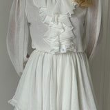Elegante minivestido de manga larga y escote alto con volantes.