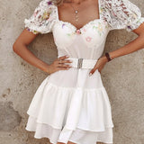 Vestido de mujer con hombros descubiertos, cinturón ancho, mangas asimétricas y falda con volantes.