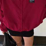 Gabardina roja con cuello alto, corte holgado y relajado, estilo streetwear.