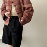 Chaqueta de lana a cuadros, cuello redondo, botonadura sencilla, hombros caídos.