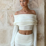 Conjunto sexy de dos piezas compuesto por un top corto con hombros descubiertos y una falda de talle alto y color liso.