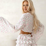 Conjunto de dos piezas compuesto por un top corto de manga larga con volantes que se atan en la parte delantera y un short con estampado floral.