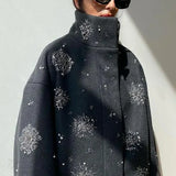 Abrigo de cuello alto adornado con perlas y lentejuelas.
