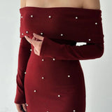 Vestido de noche largo, sin espalda y con hombros descubiertos, adornado con perlas.