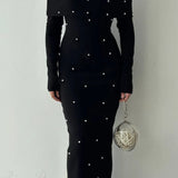 Vestido de noche largo, sin espalda y con hombros descubiertos, adornado con perlas.