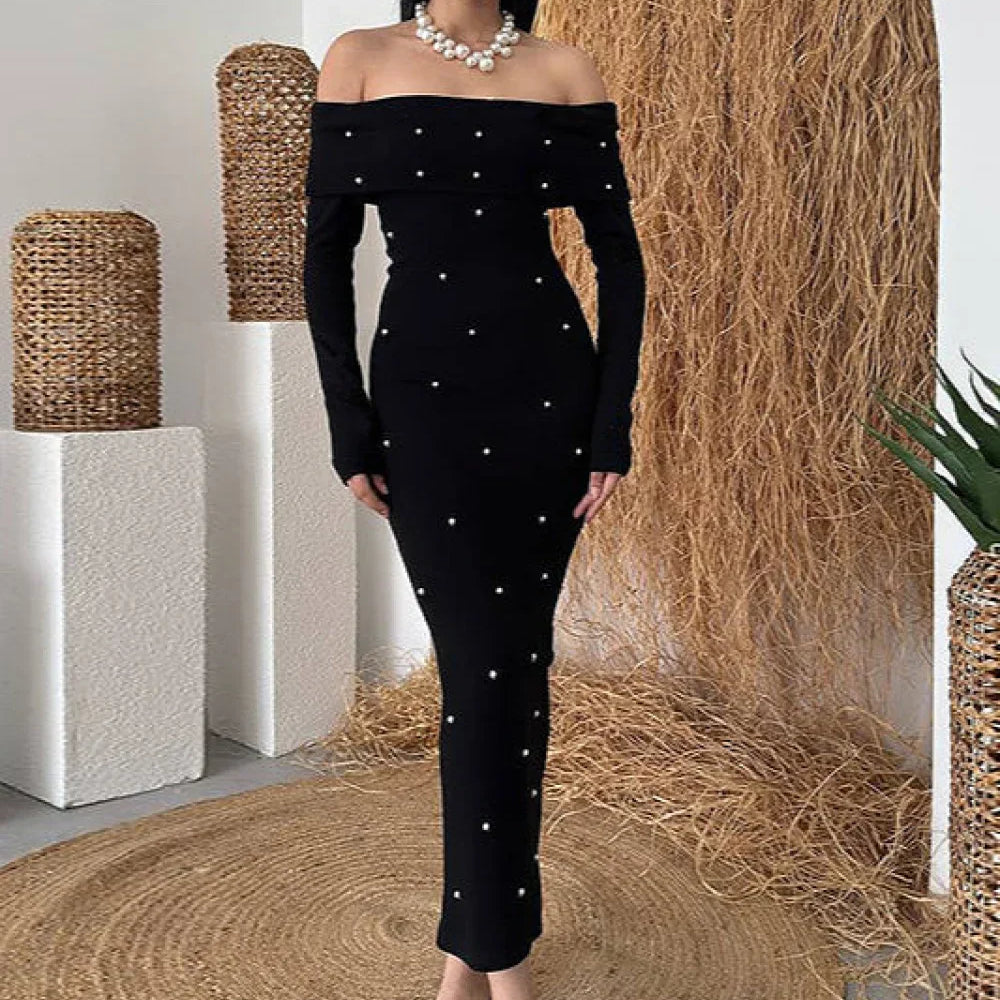 Vestido de noche largo, sin espalda y con hombros descubiertos, adornado con perlas.