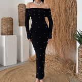 Vestido de noche largo, sin espalda y con hombros descubiertos, adornado con perlas.