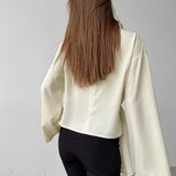 Blusa de gasa de seda beige con cintura anudada y mangas acampanadas, con cinturón para anudar.