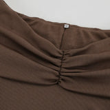 Vestido trapecio corto de punto marrón con escote en V y hombros descubiertos, cintura anudada.