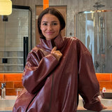 Elegante conjunto de dos piezas: chaqueta y falda de charol liso con cuello alto.