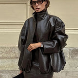 Elegante conjunto de dos piezas: chaqueta y falda de charol liso con cuello alto.