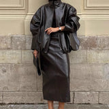 Elegante conjunto de dos piezas: chaqueta y falda de charol liso con cuello alto.