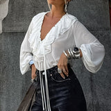 Blusa vintage con volantes, escote en pico, mangas farol y cierre de lazo. Escote en pico y mangas farol.