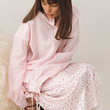 Blusa rosa estructurada con mangas largas y cintura atada.