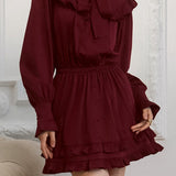 Elegante mini vestido de manga larga y encaje, adornado con lazo, corte trapecio.