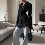 Blazer suave con mangas largas y cintura ajustada, adornado con paneles de encaje negro.