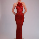 Vestido de noche ajustado con cuello halter y pedrería, adornado con flores 3D y pedrería en la cintura.