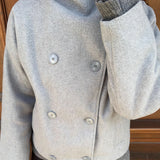 Elegante abrigo de lana liso con botones y cuello alto.