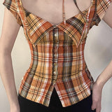 Blusa corta de cuadros, cintura ajustada, cuello con lazo y botones en la parte delantera.