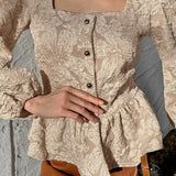 Blusa sofisticada con mangas abullonadas, cuello cuadrado y tejido jacquard.