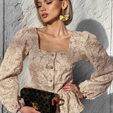 Blusa sofisticada con mangas abullonadas, cuello cuadrado y tejido jacquard.