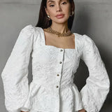 Blusa sofisticada con mangas abullonadas, cuello cuadrado y tejido jacquard.