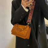 Bolso de hombro de piel sintética con cadena de metal.