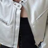 Chaqueta corta de cuero plateada con cuello alto y botones a presión.