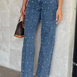Jeans con cintura asimétrica, top cruzado, detalle de perlas y piernas rectas deshilachadas.