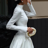 Vestido corto y sencillo con cuello alto, cintura ajustada y mangas largas.
