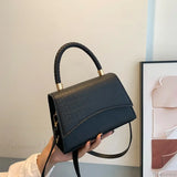 Bolso de hombro informal en piel sintética maciza con asa superior.