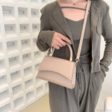 Bolso de hombro informal en piel sintética maciza con asa superior.