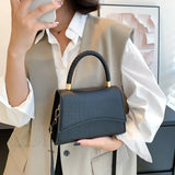 Bolso de hombro informal en piel sintética maciza con asa superior.