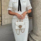 Elegante vestido midi de tweed adornado con perlas y un lazo.